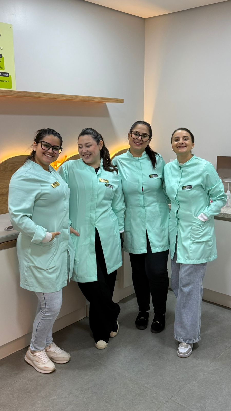 Equipe da NH Vacinas com uniformes mint sorrindo juntas