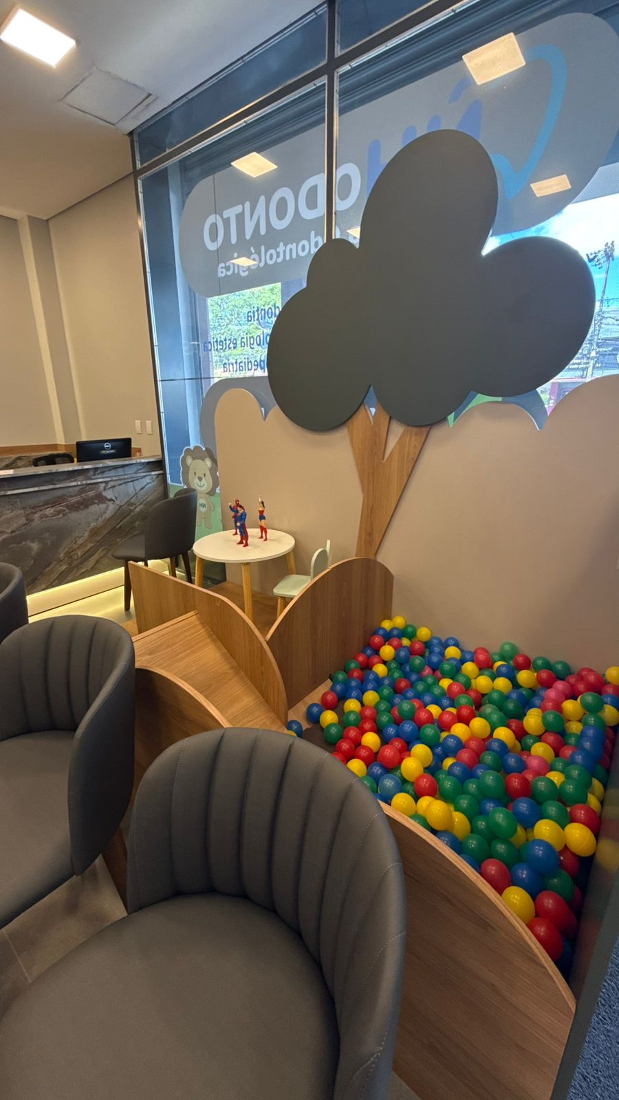 Área infantil com piscina de bolinhas coloridas e árvore decorativa